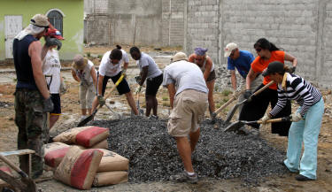 Team members ready a big batch of cement for house floor