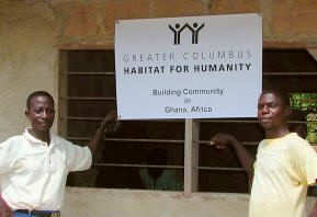 Habitat homeowners proudly standing by Habitat banner