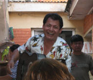 Smiling latino man playing guitar in crowded restaurant
