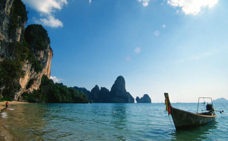 Longtail boat amidst cliffs and blue sky